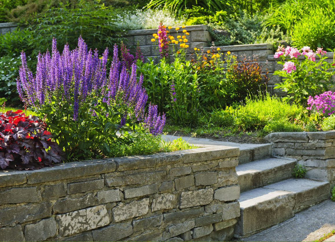 Natural stone landscaping in home garden with steps and flowerbeds